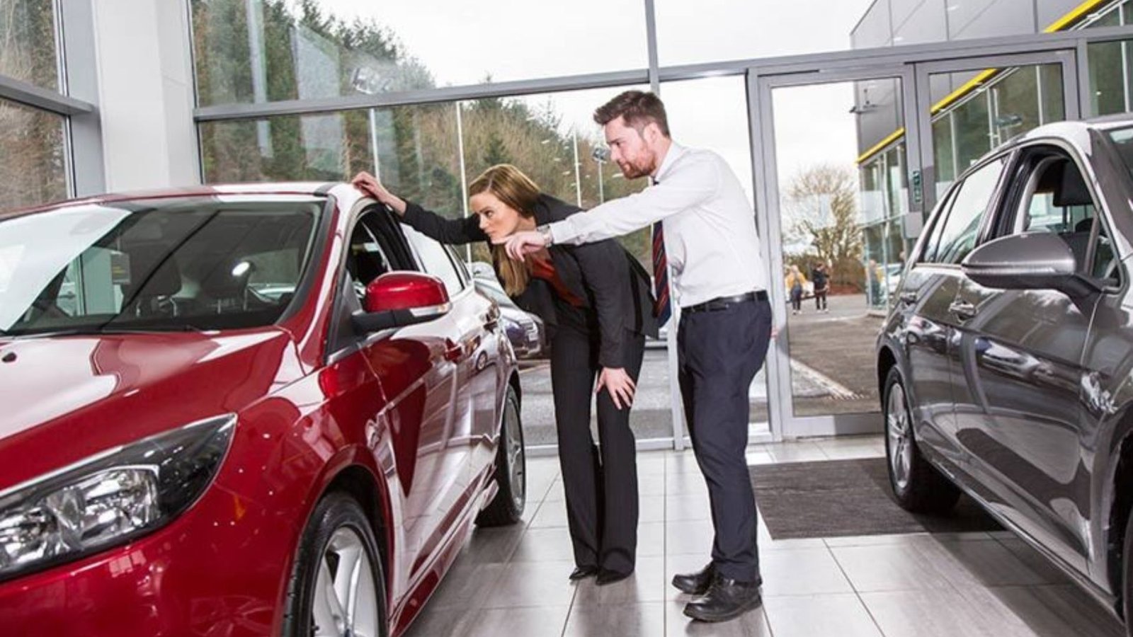 2 People Looking at a Red Car Showing What to Look for When Buying a Used Car